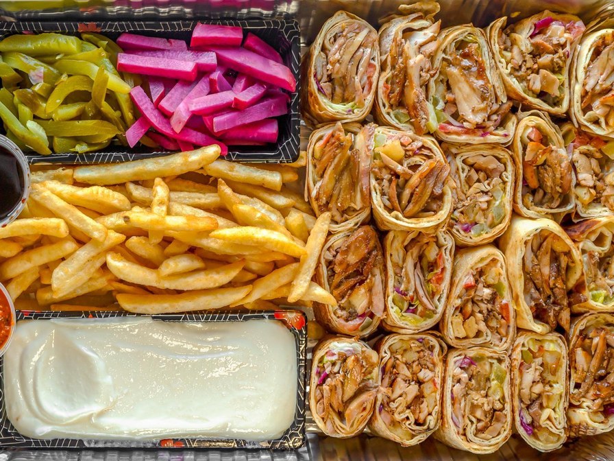 Shawarma family plate with four sliced shawarma wraps, fries, pickles and garlic sauce
