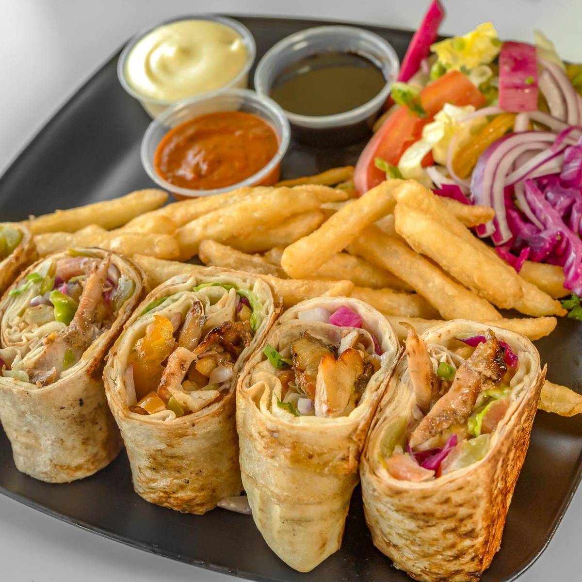 Shawarma family plate with four sliced shawarma wraps, fries, pickles and garlic sauce